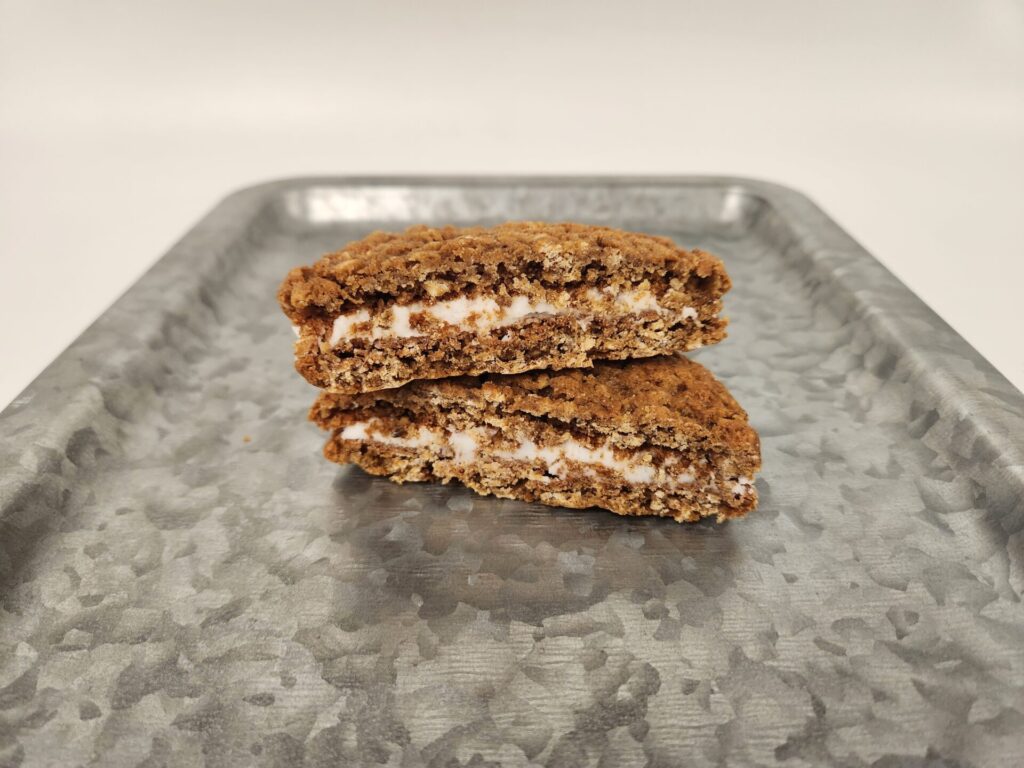 The inside of a Homemade Oatmeal Cookie Creme Pie with smooth vanilla filling between two soft, golden-brown oatmeal cookies.